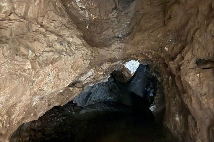A cave interior with rugged rock formations and a visible water pool. 2
