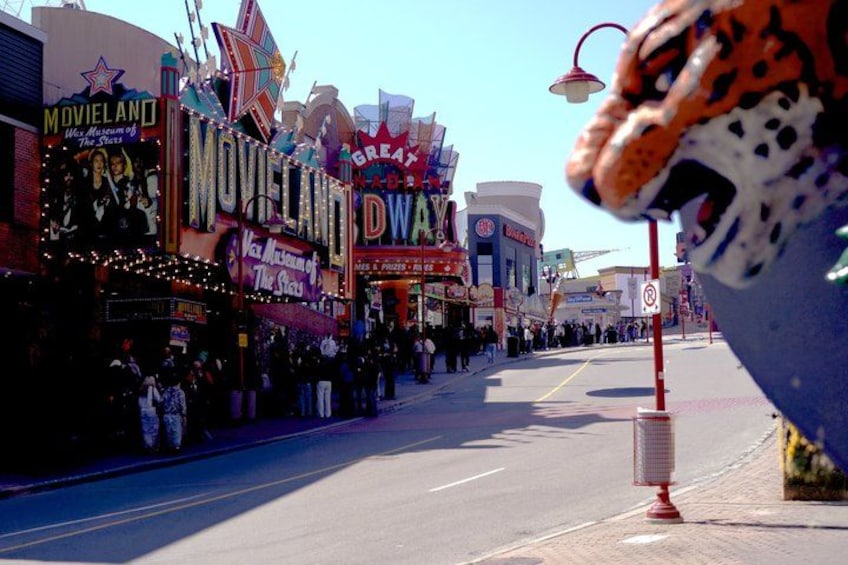A street lined with colorful neon signs and a large, decorated elephant statue. 4