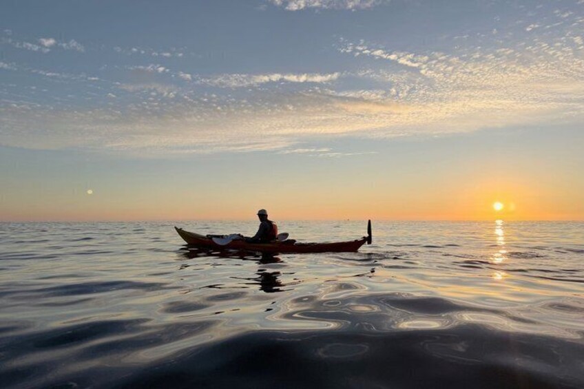 A person kayaking on calm water during sunset. 5