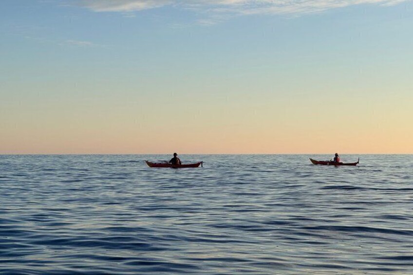 Two canoes on calm water with a clear sky. 3