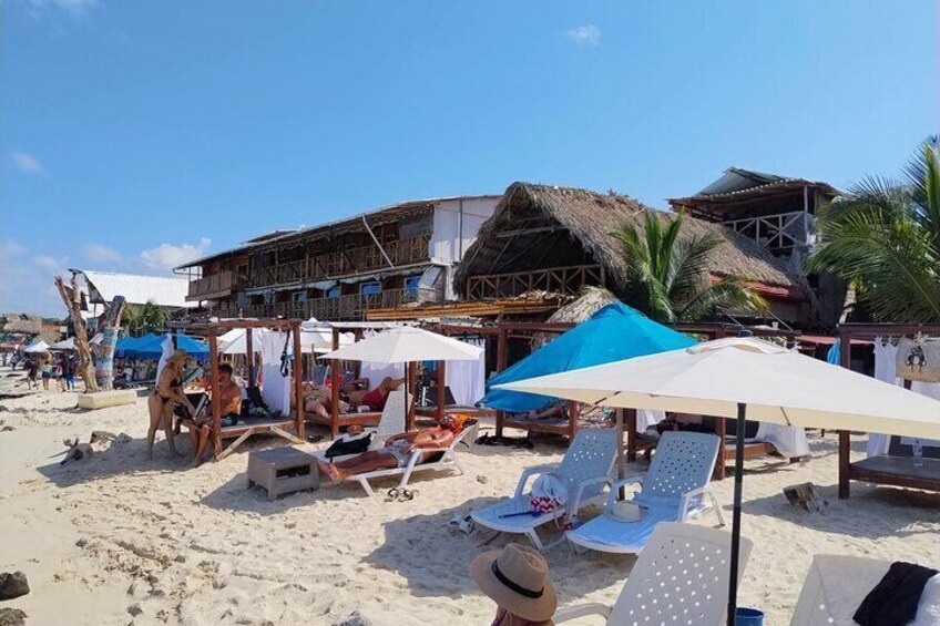 A beach with sun loungers, umbrellas, and a wooden structure. 2