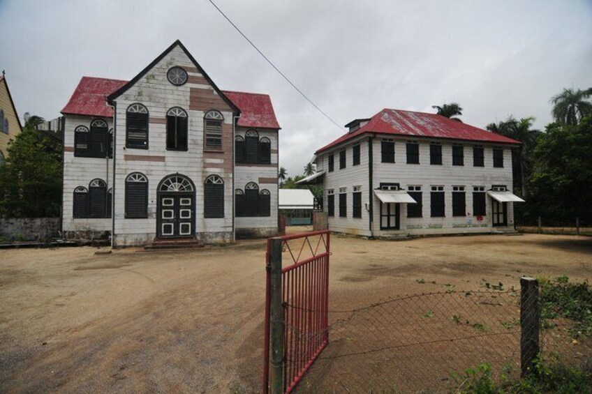 Two white buildings with red roofs and a red gate in the foreground. 2