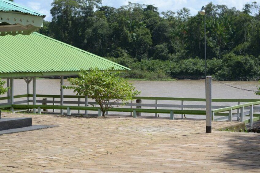 A covered pavilion with a green roof, a brick pathway, and a chain-link fence. 4