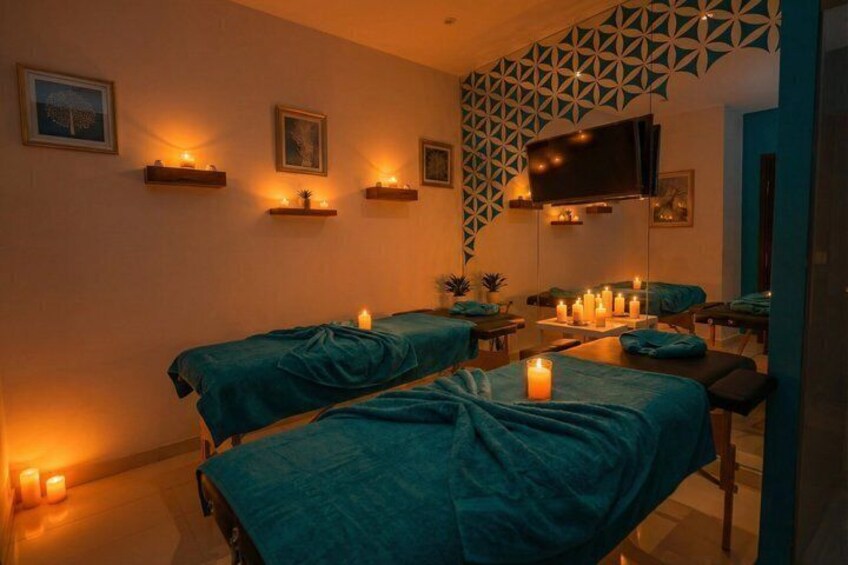 Une salle de spa avec deux lits, des bougies et un téléviseur fixé au mur. 5