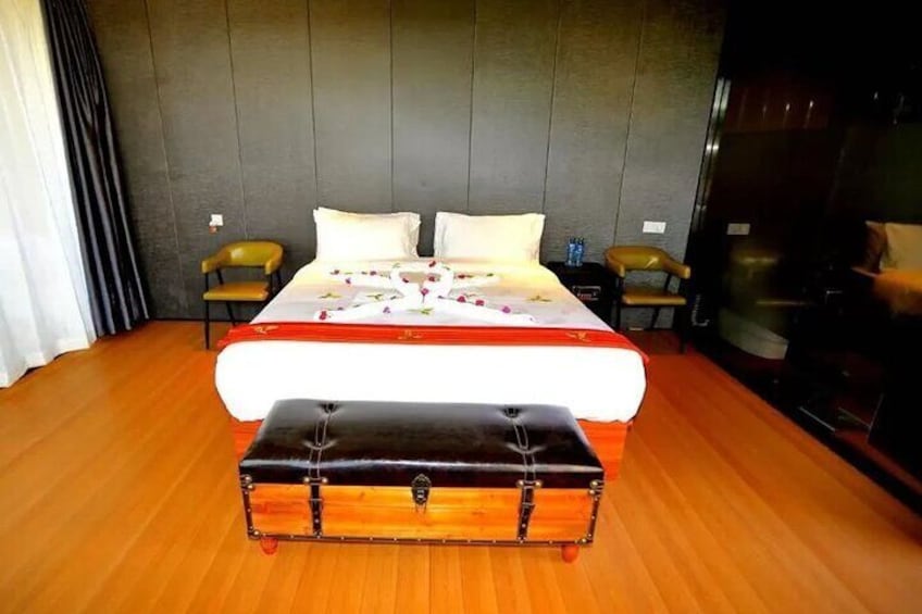 A hotel room with a large bed, a wooden bench, and a dark wall. 5