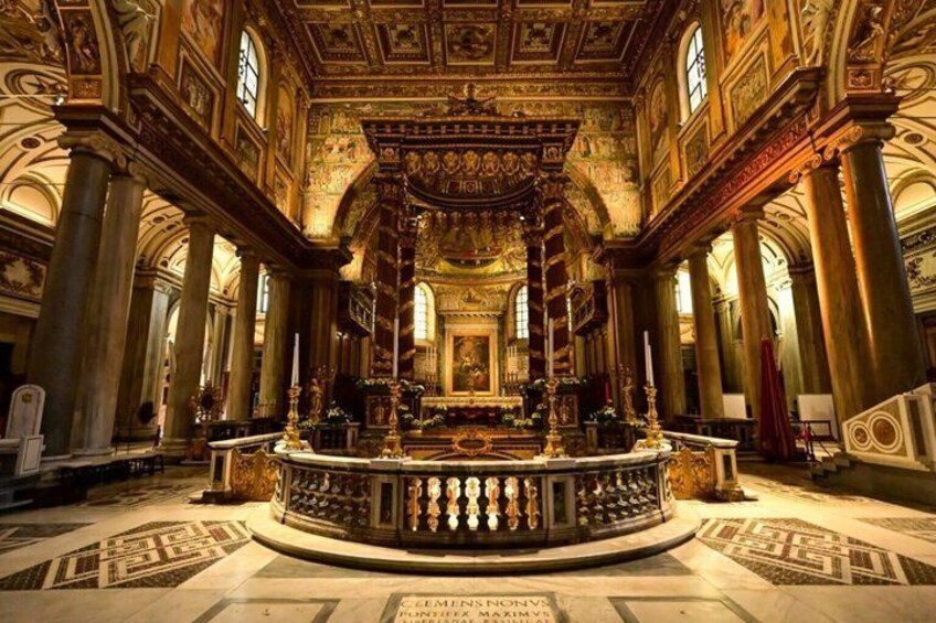 Interior de una iglesia ornamentada con altar central, columnas y detallados trabajos artísticos en el techo. 3