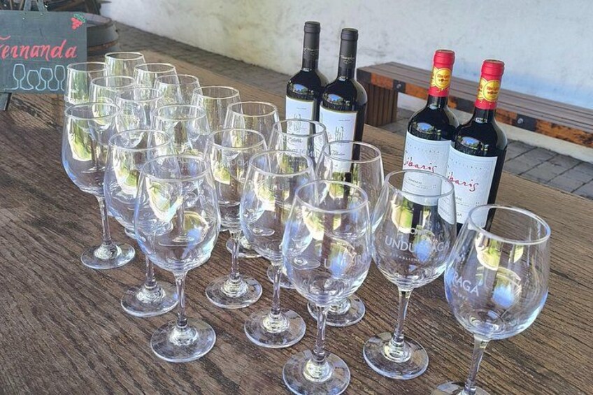 Una mesa de madera con copas de vino vacías y botellas de vino. 5