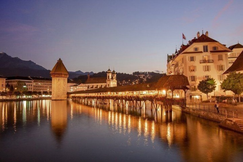 Un río tranquilo con un puente, edificios y una torre reflejándose en el agua. 3