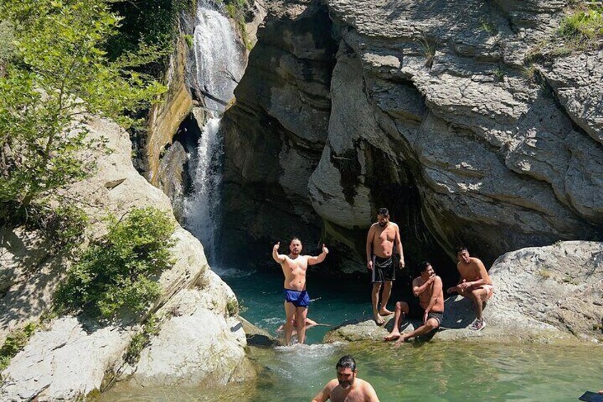 Un grupo de personas junto a una fuente de agua natural rodeada de terreno rocoso. 5