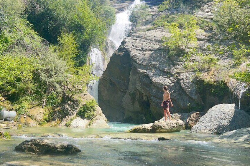 Una cascada, agua cristalina, rocas y una persona de pie sobre una roca. 1