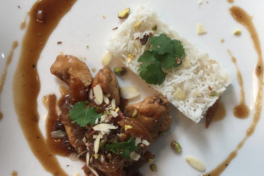 A dish with white rice, chicken, and garnishes. 2
