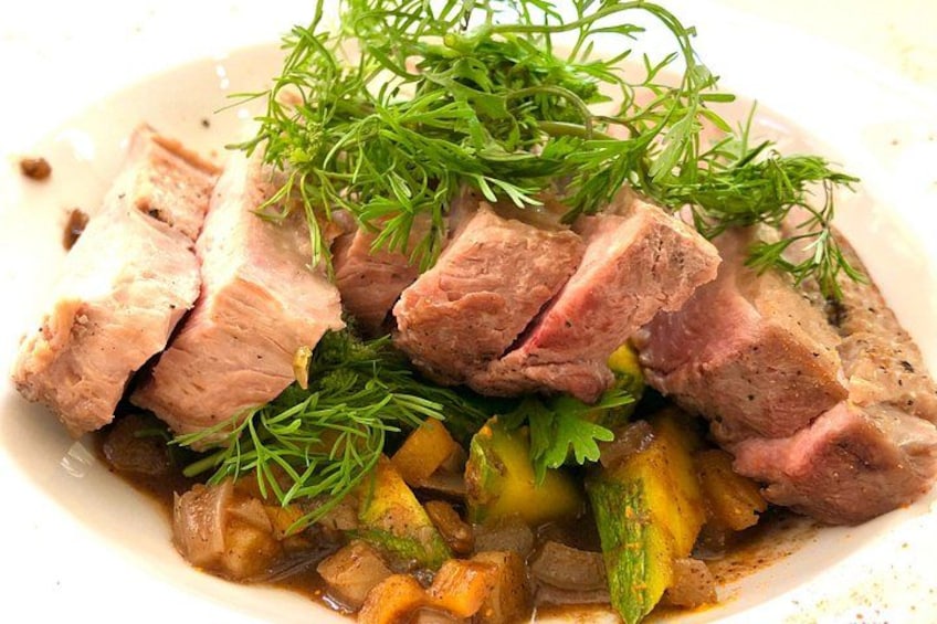 A dish with sliced meat, vegetables, and herbs. 4