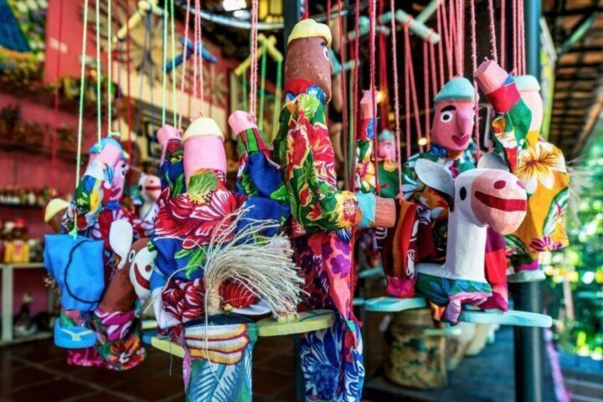 Figuras de madera coloridas con sombreros y accesorios colgando de una estructura. 5