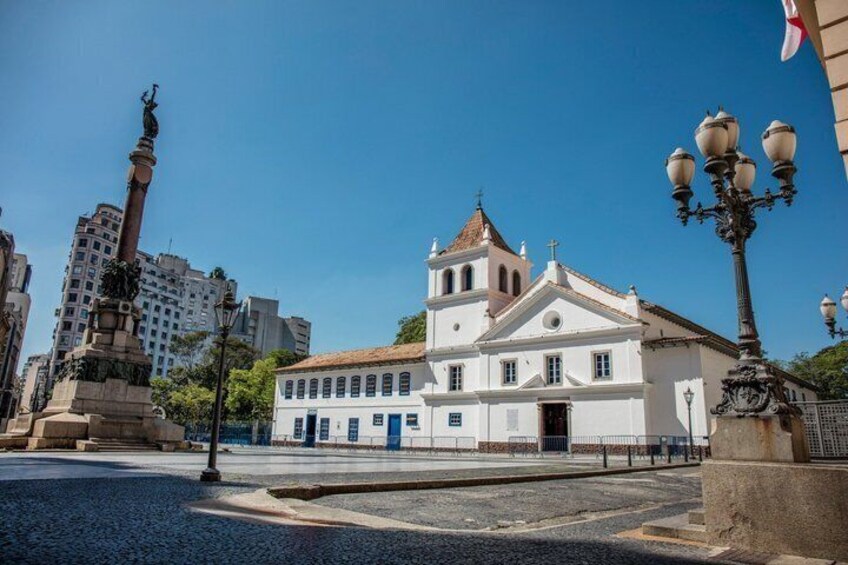 Un edificio histórico con una torre de campanas, una estatua y un farol. 4