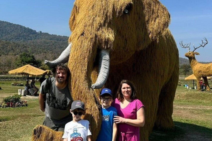 A large elephant statue, a person in a blue shirt, and a person in a pink shirt. 4