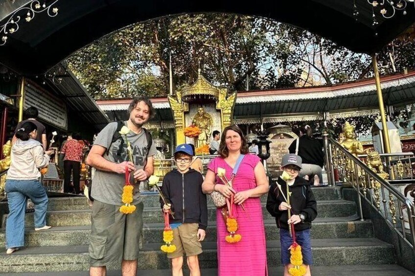 A group of people at a temple with golden statues and a staircase. 5