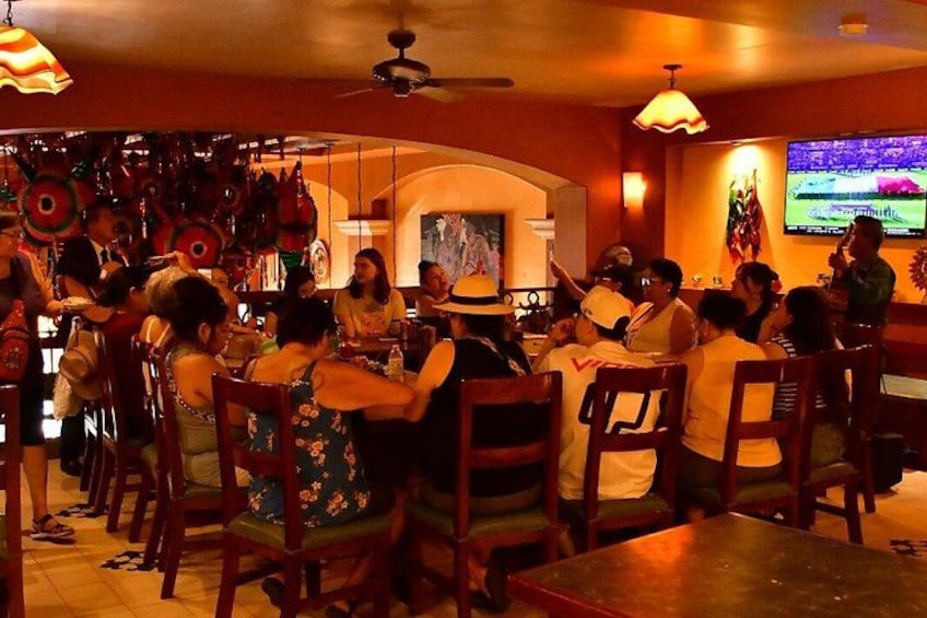 A restaurant interior with wooden chairs, tables, and hanging decorations. 4