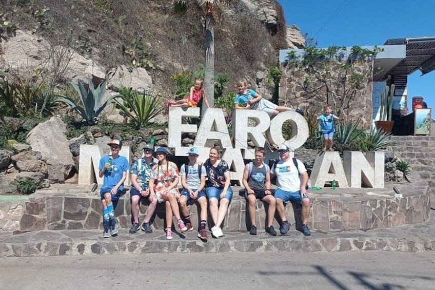 A group of people sitting in front of a large sign with the text 'EARO MAN'. 3