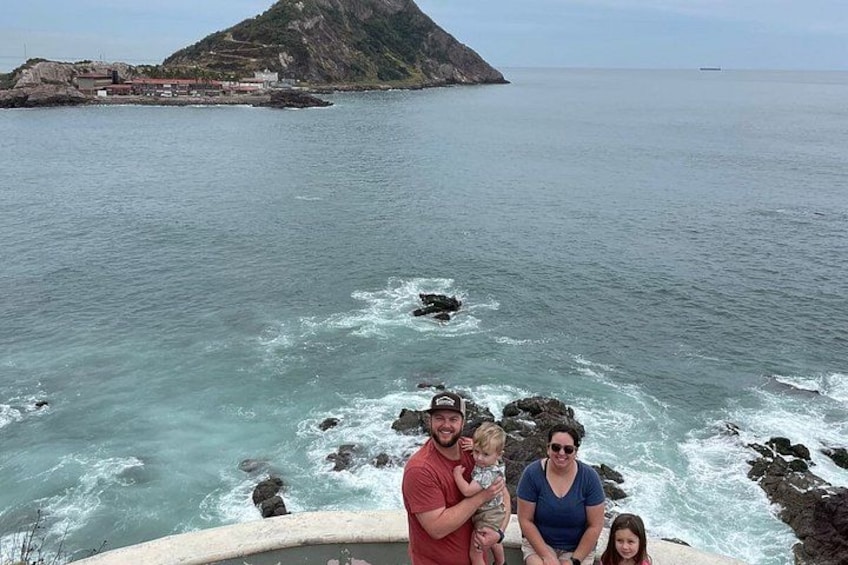 A family by a rocky coastline with waves crashing against the rocks. 2