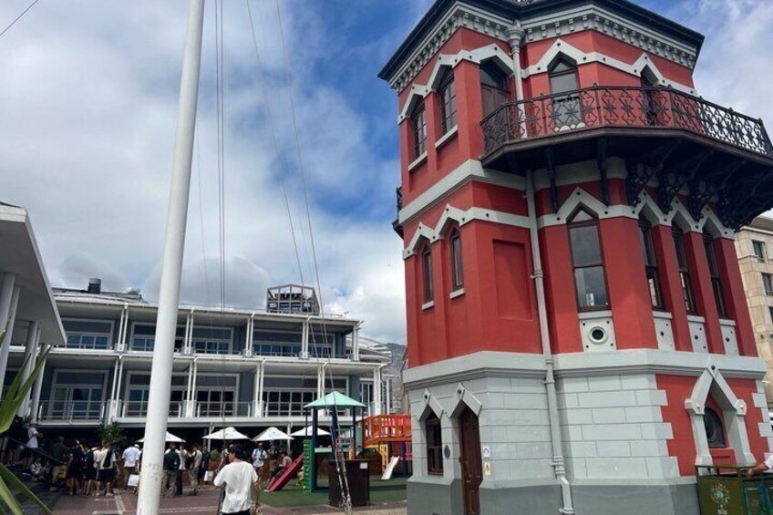 Et rødt og hvidt tårn med balkon, en hvid bygning med blåt tag og en klar himmel. 3