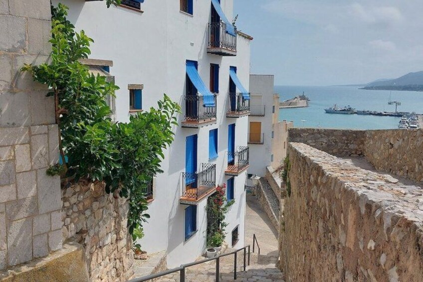 Un edificio sul lungomare con balconi azzurri che si affaccia su un porto con barche. 2
