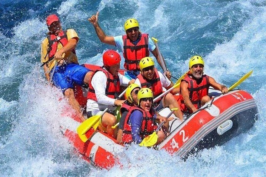 Un grupo de personas en un bote inflable rojo navegando entre aguas agitadas. 1