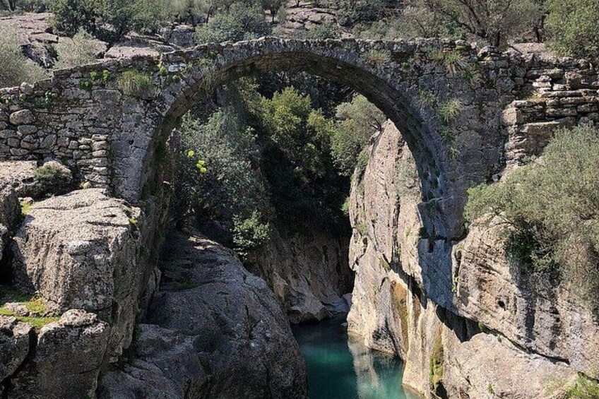Un antiguo puente de piedra que se arquea sobre un río. 3