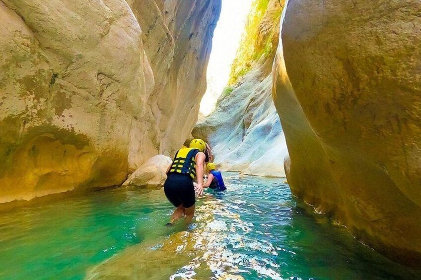 Una persona en un cañón con agua cristalina, rodeada de grandes formaciones rocosas. 5