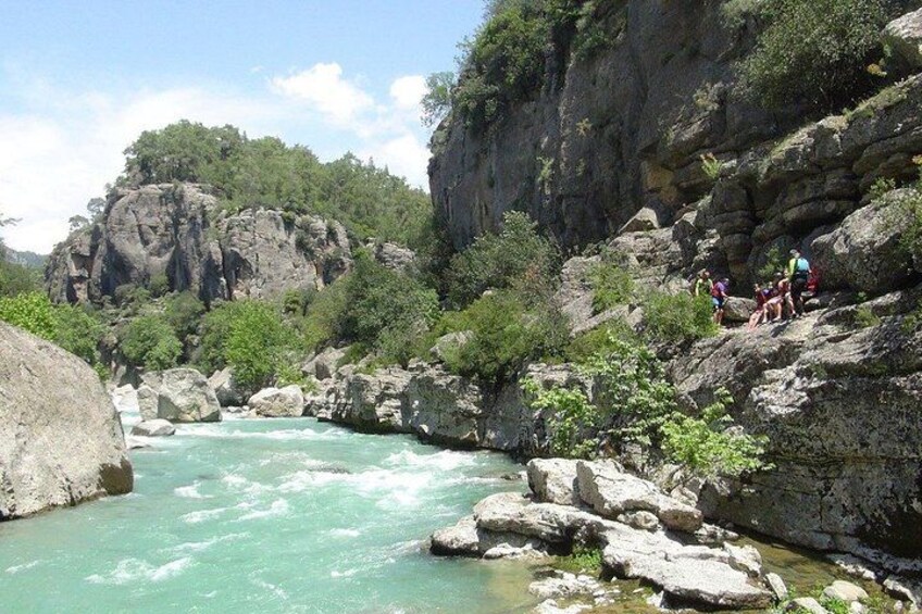 Un río fluye por un desfiladero rocoso, con personas de pie sobre las rocas. 2