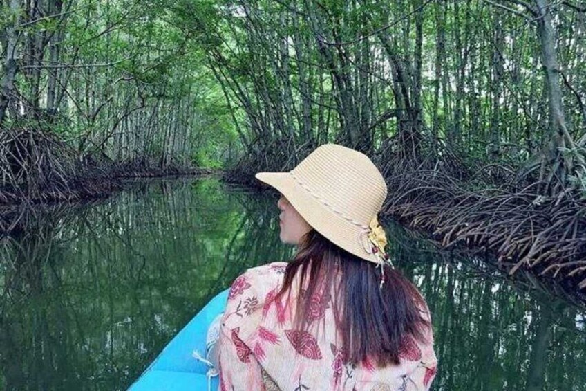 Een persoon in een boot op een rustig waterweg, omringd door dichte mangrovebomen. 5
