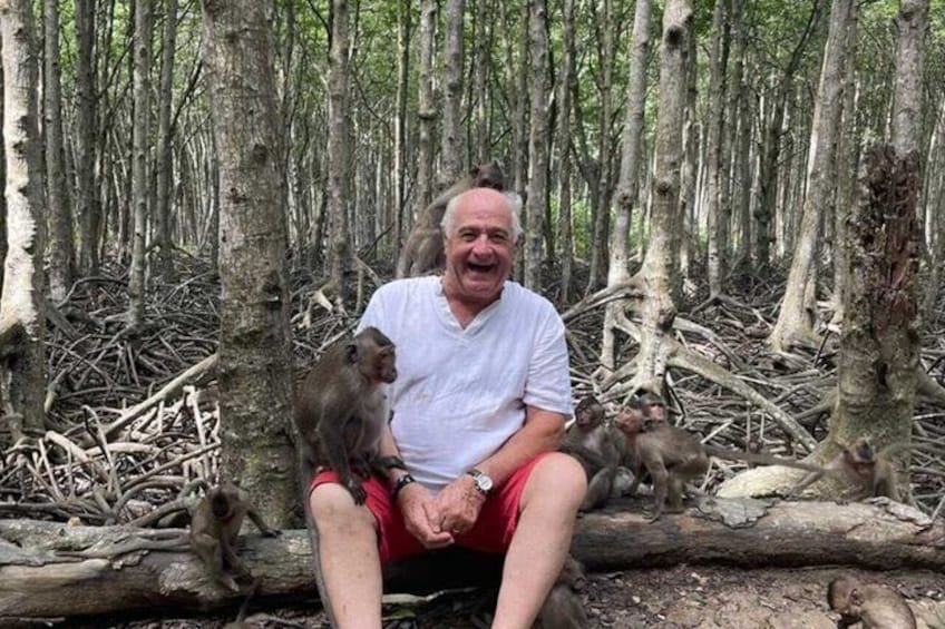 En man sitter på en trädstam omgiven av träd i en skog. 1
