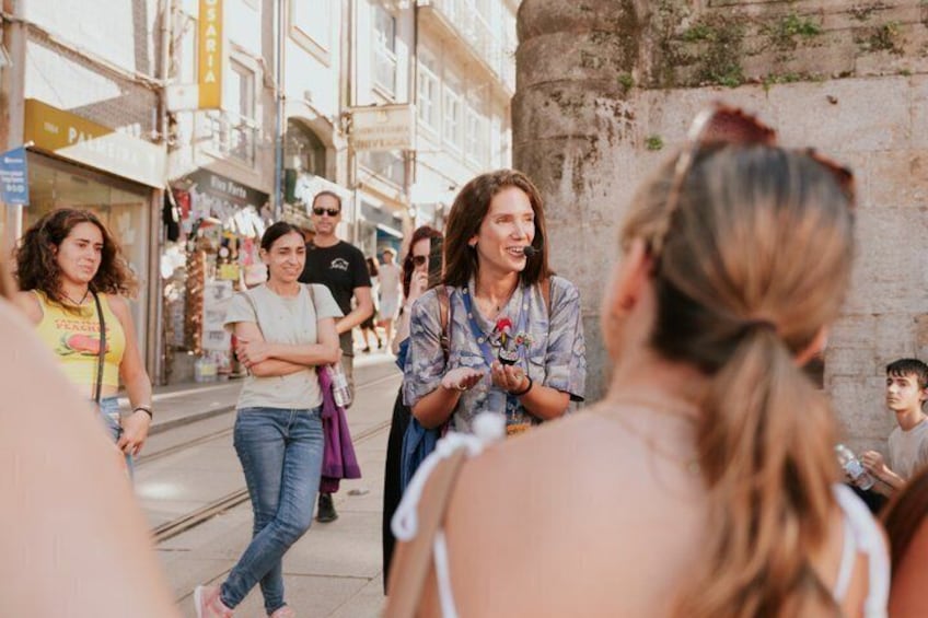 Un grupo de personas caminando por una calle con tiendas y un muro de piedra. 3