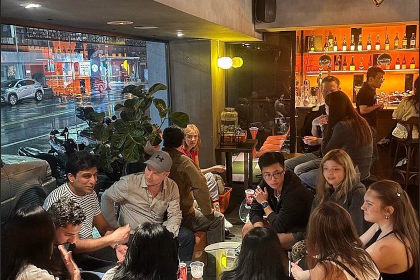 A group of people sitting at a bar with a large window displaying a street scene. 4