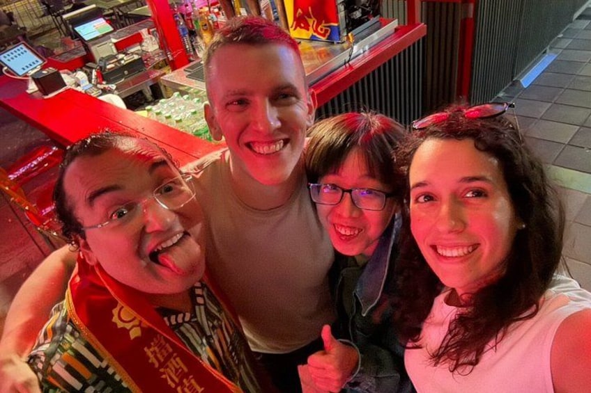 A group of people in a brightly lit indoor setting with red and yellow decor. 3