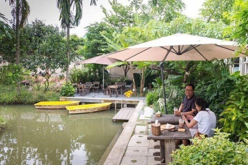 A riverside dining area with wooden tables, yellow boats, and a large umbrella. 5