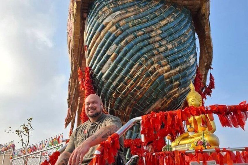 A large Buddha statue with a golden head and a body wrapped in blue and red fabric, surrounded by red decorations. 3