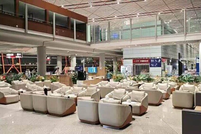 A spacious airport lounge with rows of seating and a high ceiling. 1
