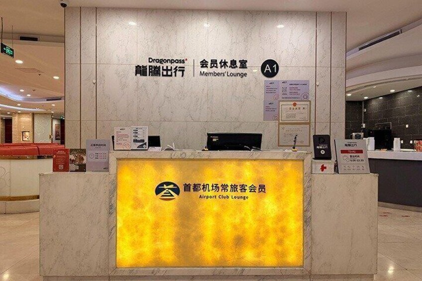 A reception desk with a Dragonpass logo and a sign for the Airport Club Lounge. 2