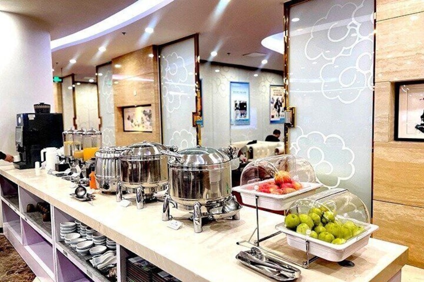 A buffet setup with food containers, a fruit display, and a coffee machine. 5