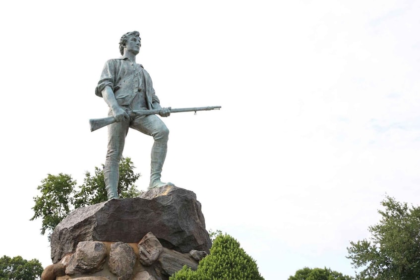 A statue of a person holding a rifle on a rock. 3