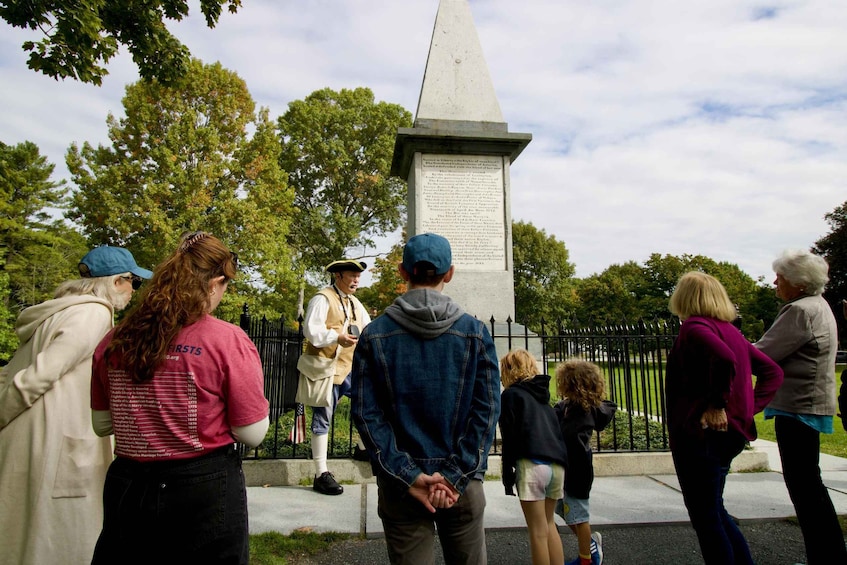 A group of people standing in front of a monument with a pyramid-shaped top. 4