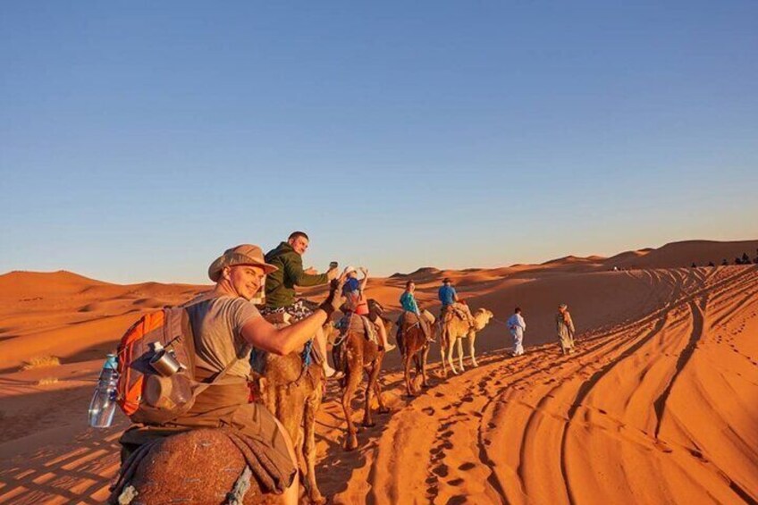 En grupp människor som rider på kameler i ett ökenlandskap med sanddyner. 4
