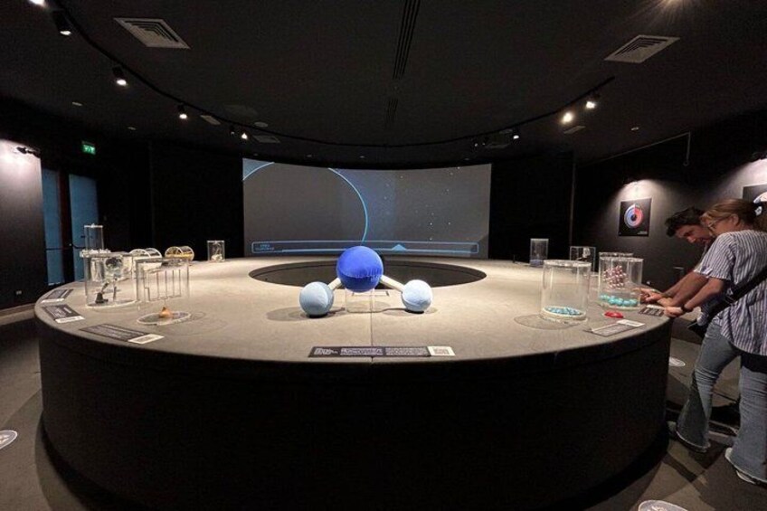 A round table with scientific models and a projection screen in a museum. 3