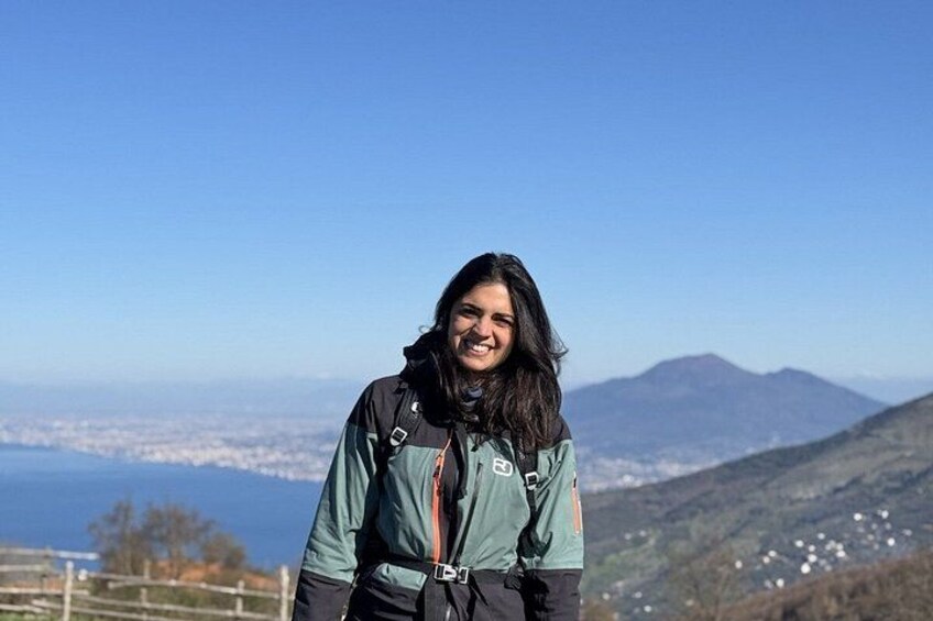 A person standing on a hill with a cityscape and mountains in the background. 1