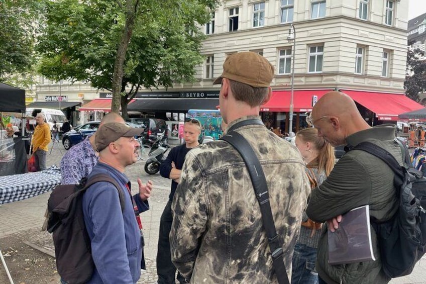 A group of people standing on a sidewalk, engaged in conversation. 4