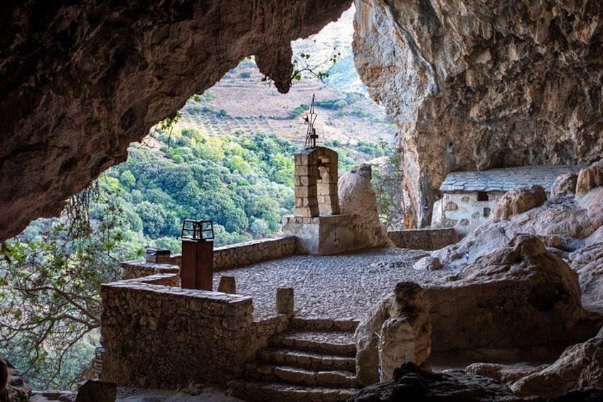 Una grotta con una struttura in pietra e vista su una valle boscosa. 3