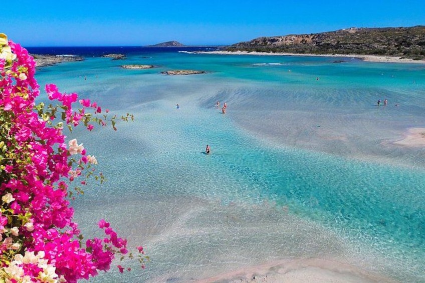 Una spiaggia costiera con acque turchesi cristalline, una riva sabbiosa e colline rocciose in lontananza. 1