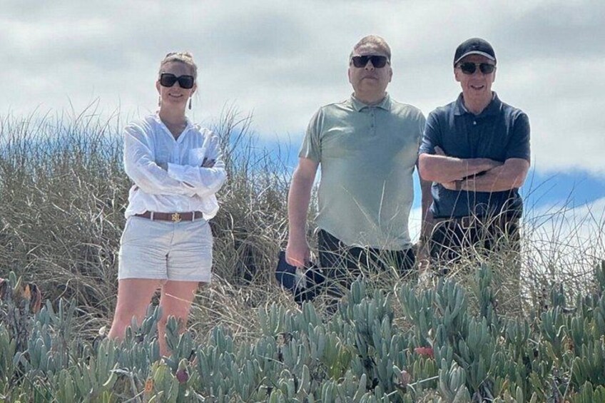 Three people standing in a field with tall grass and cacti. 2