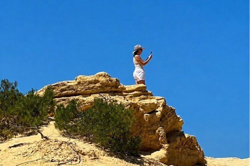 Una persona in piedi su una formazione rocciosa, con un cielo azzurro limpido sullo sfondo. 5