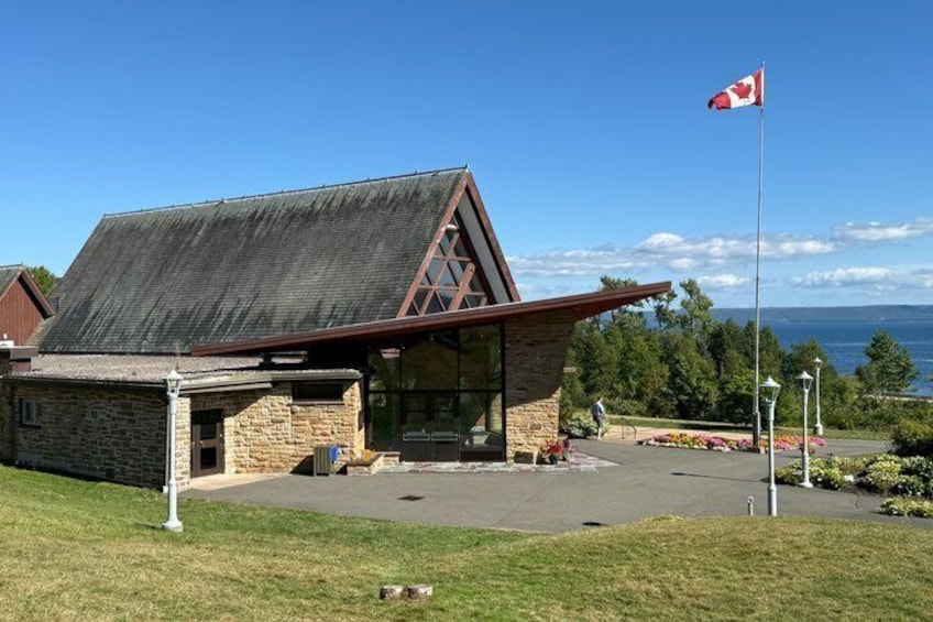 A stone building with a sloped roof, a glass entrance, and a Canadian flag. 5